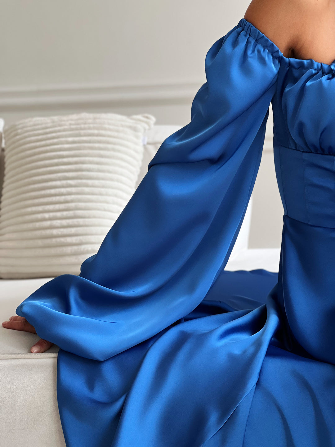 royal blue satin maxi dress featuring long bishop sleeves, a structured corset waist, and a gathered tie-front bust. This flowing gown with a dramatic thigh-high slit is an elegant choice for a black-tie wedding guest, a formal holiday gala, or an upscale evening dinner.