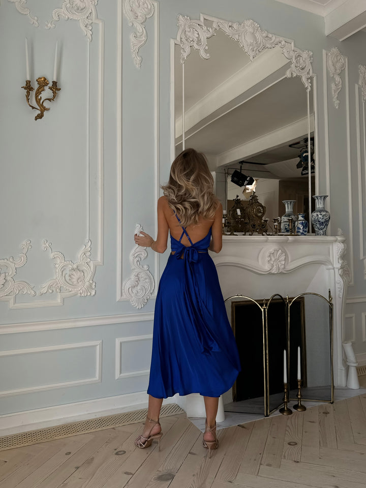 Back view of royal blue silk midi dress showing open back and bow tie closure