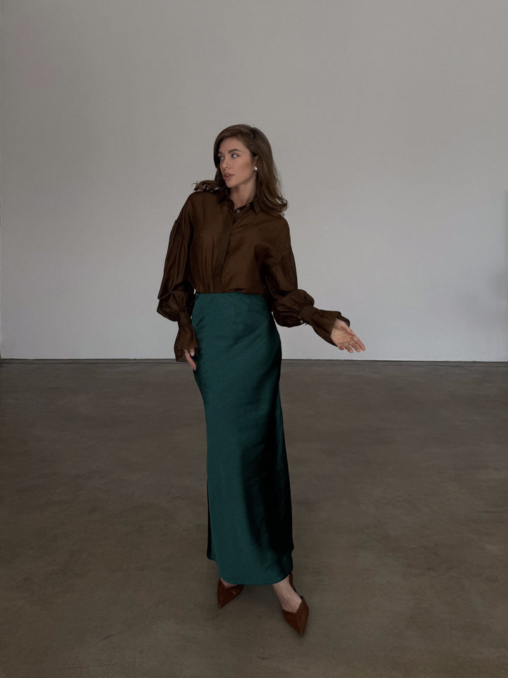 Full-length front profile of a high-waisted forest green slip skirt demonstrating an elevated casual aesthetic.