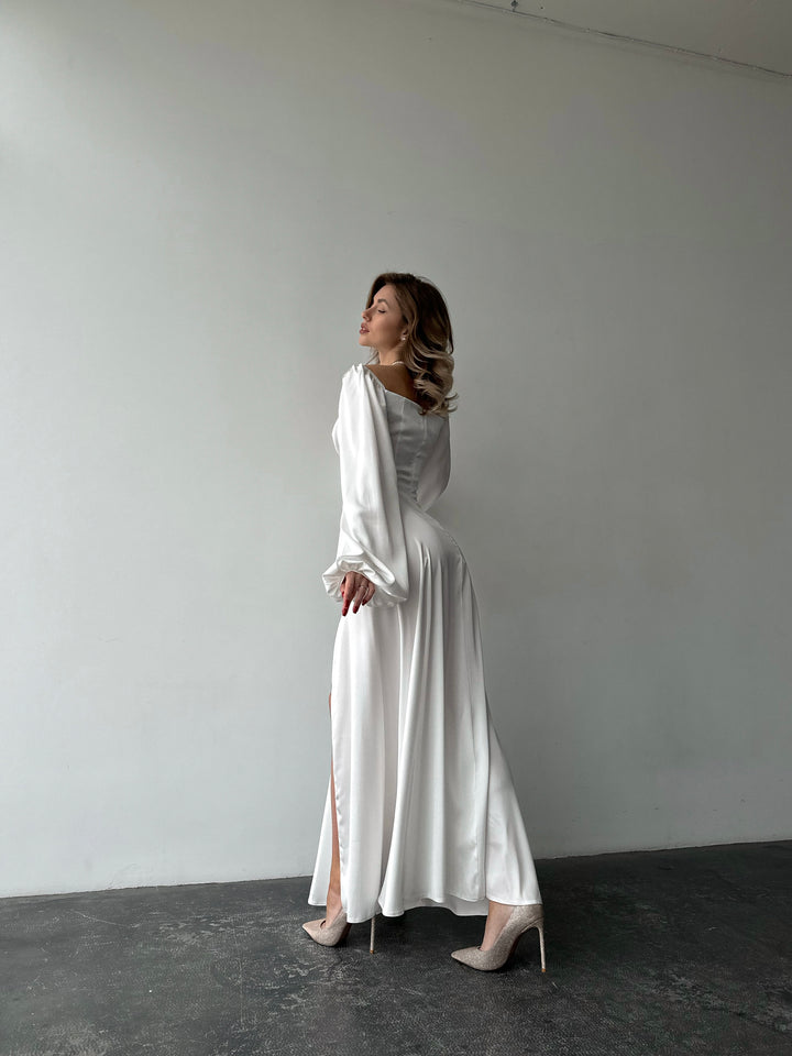 Flowing white satin gown with a classic sweetheart neckline, bishop sleeves, and a floor-sweeping skirt. A gorgeous formal event or reception ensemble.