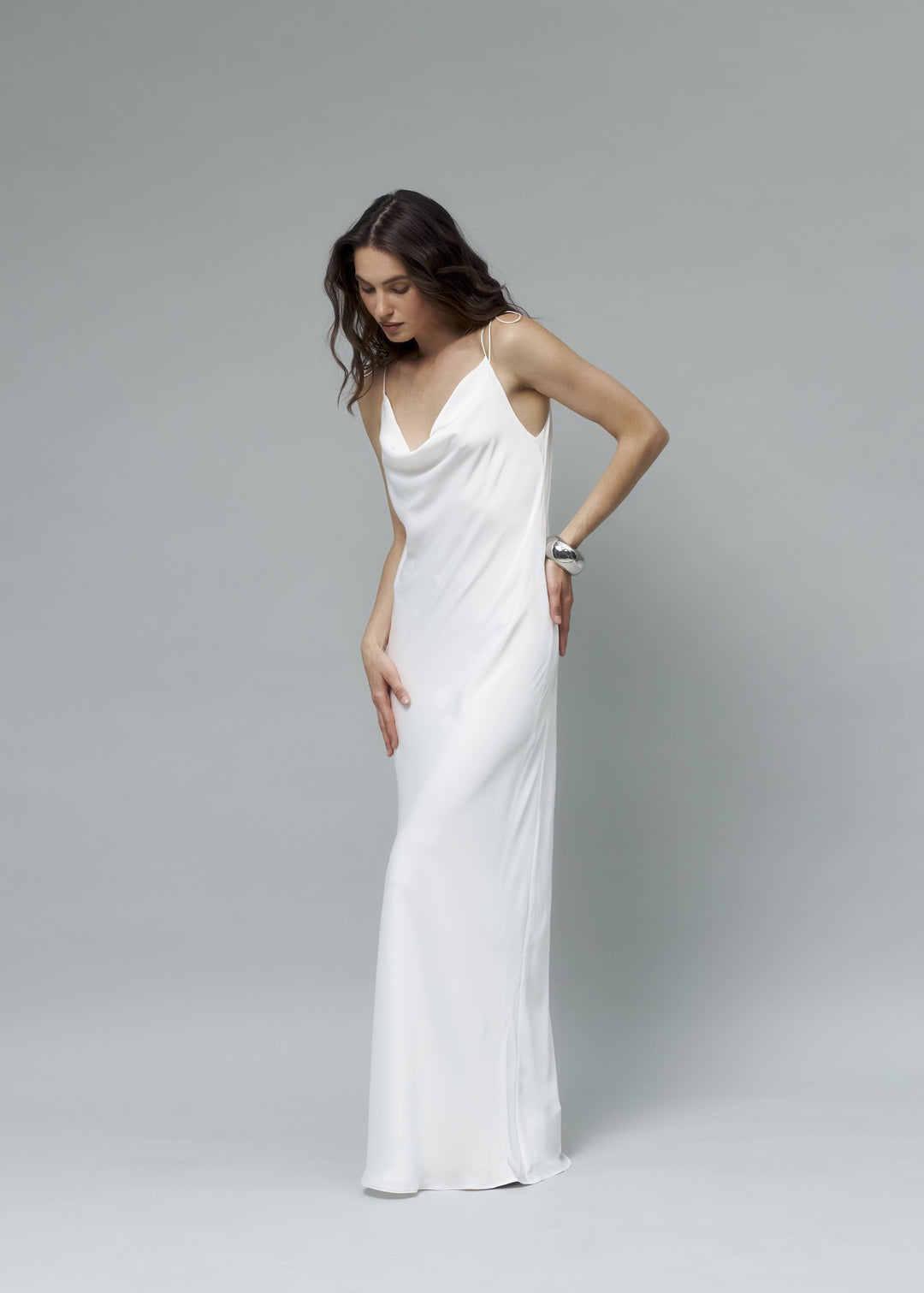 Woman wearing a white silk maxi dress against a gray background
