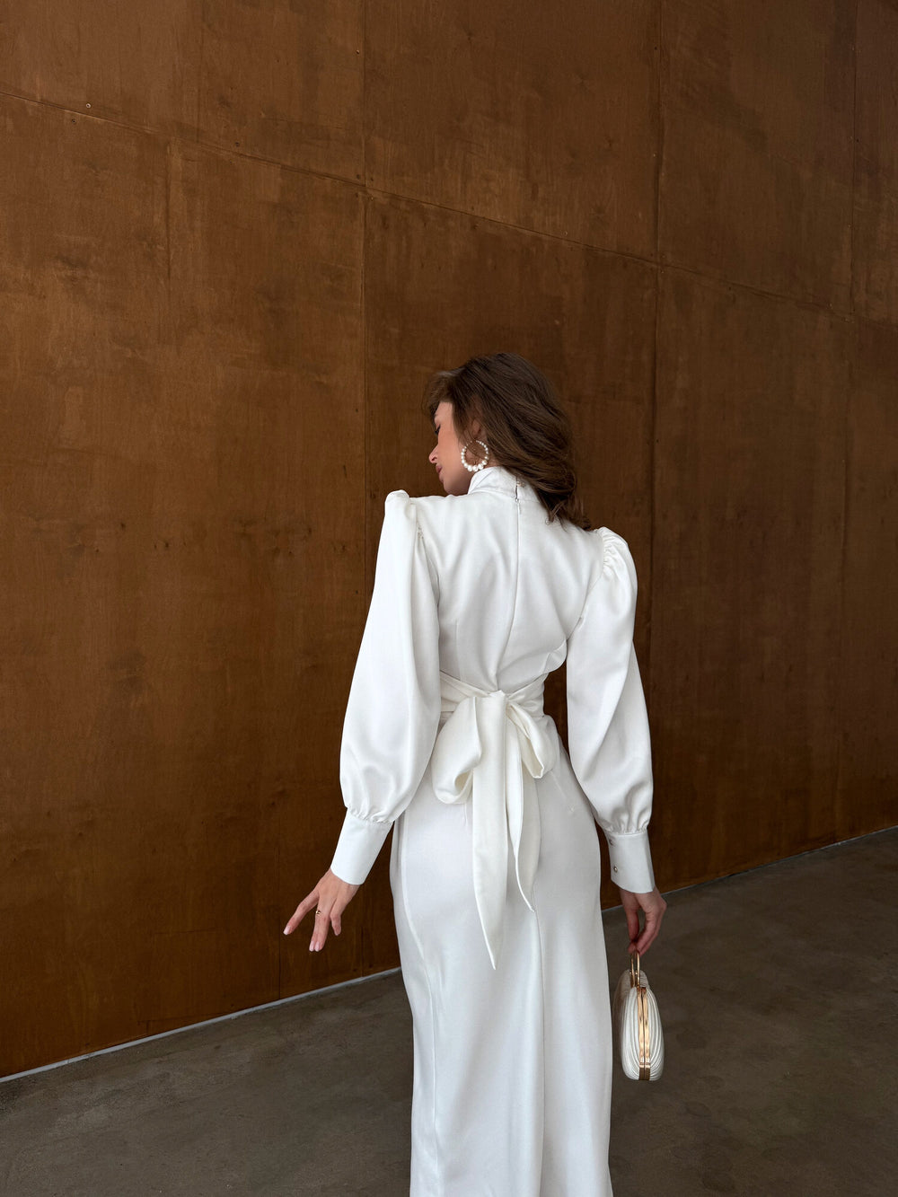 Back view of white satin midi dress showing bow tie closure, balloon sleeves and fitted skirt — civil wedding look