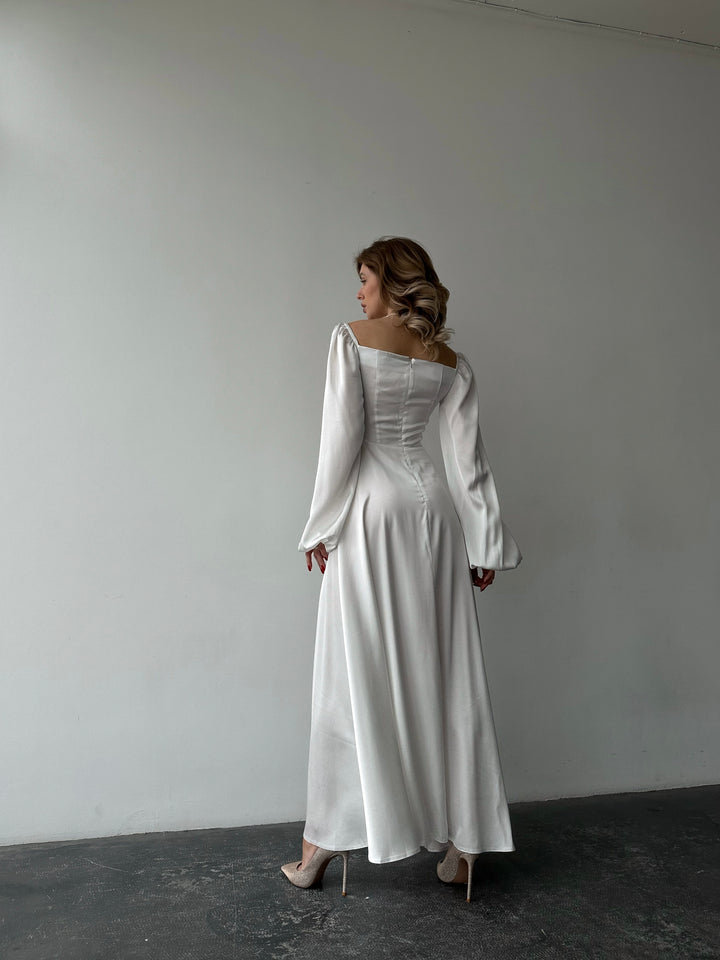 Premium white silk-like maxi dress featuring delicate draped sleeves and a leg slit. An elegant outfit choice for an upscale resort vacation aesthetic.
