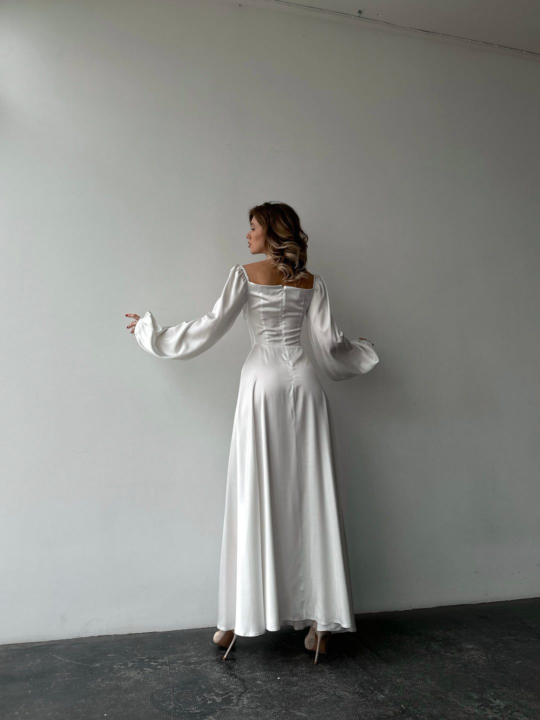 Chic white silk formal maxi dress with on-or-off shoulder puff sleeves. A pristine aesthetic perfect for a fashionable summer cocktail dress look.