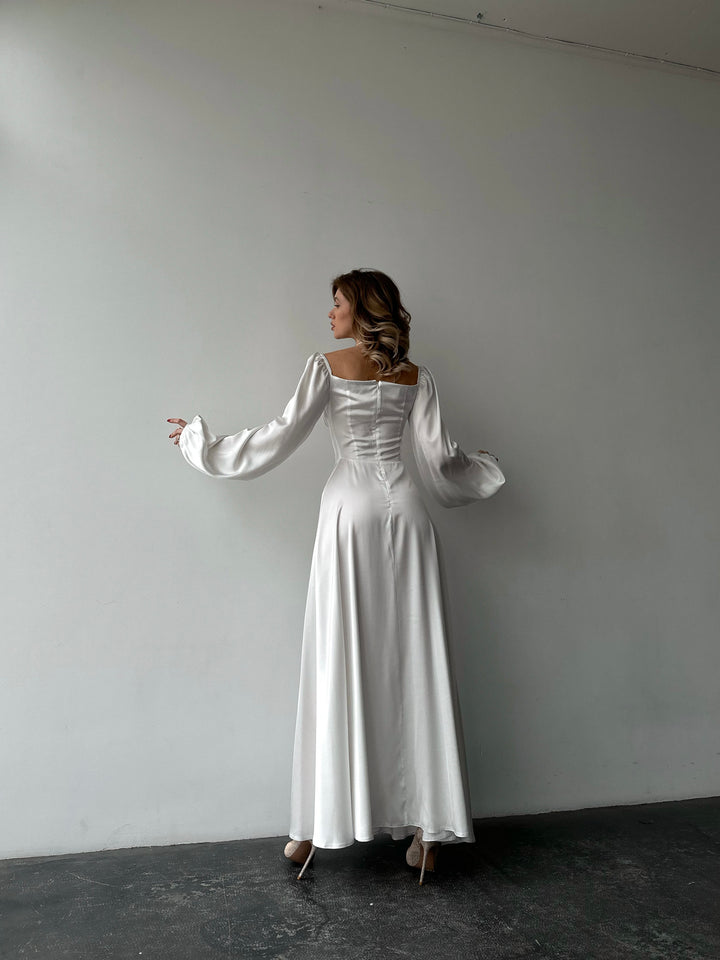 Chic white silk formal maxi dress with on-or-off shoulder puff sleeves. A pristine aesthetic perfect for a fashionable summer cocktail dress look.